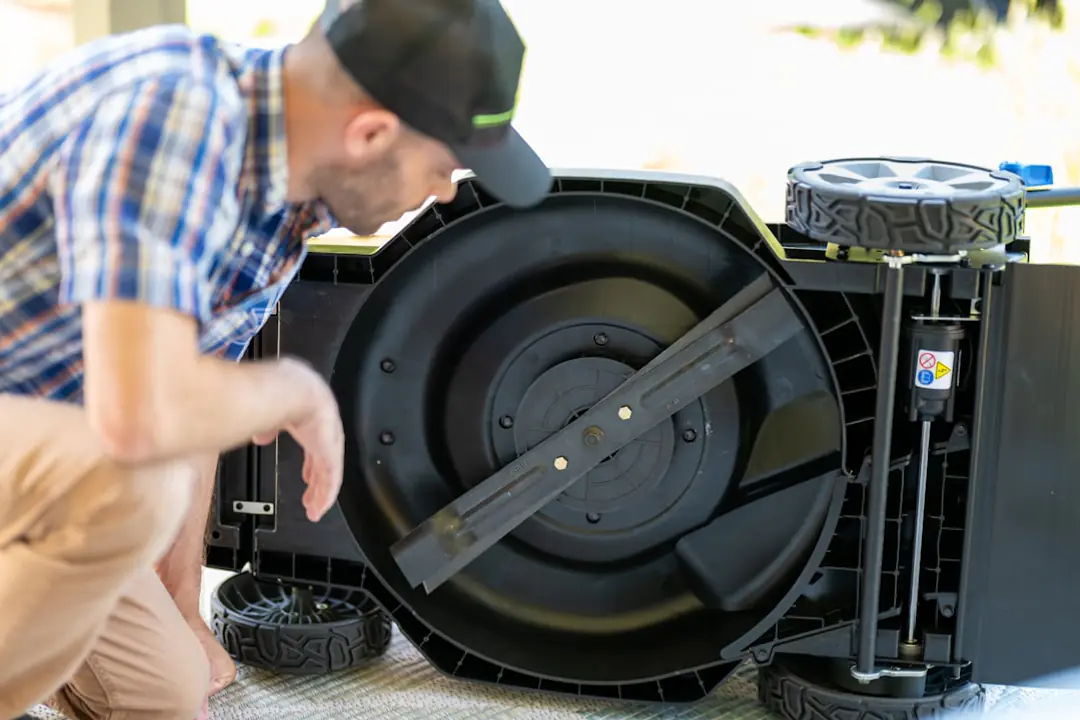 Robot tondeuse compact travaillant de jour sur une pelouse bordée de vivaces dans un jardin français