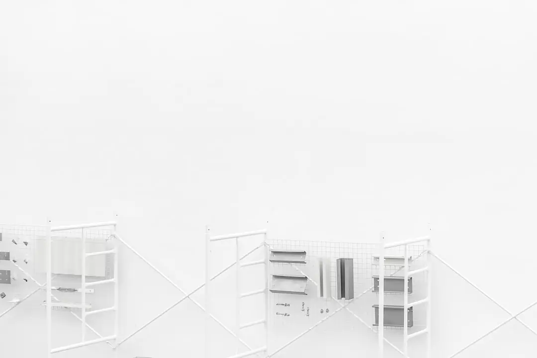 Jardinier retirant des herbes à la gouge dans une allée gravillonnée, avec paillage naturel dans le massif voisin