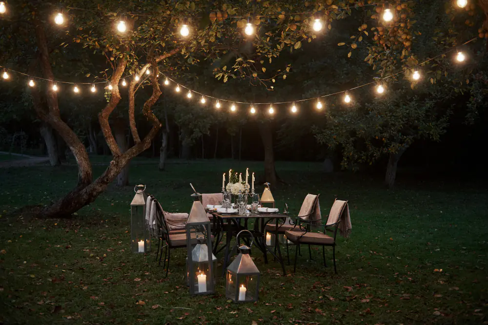 Terrasse de jardin française au crépuscule, lanternes à bougies LED posées loin des plantes sèches