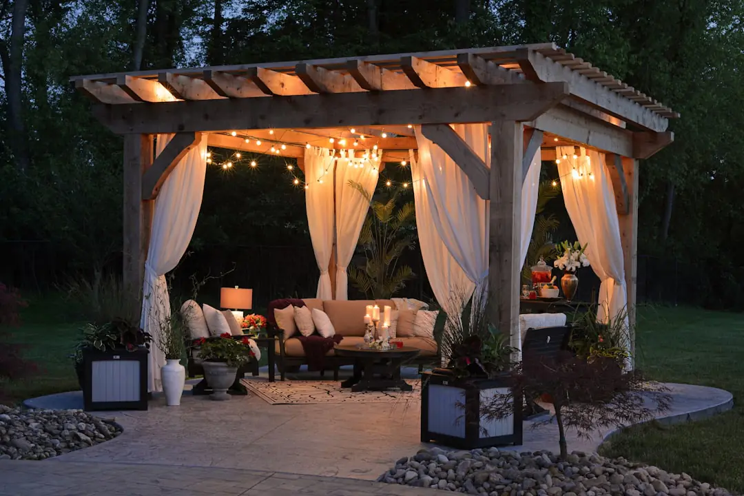 Pergola légère en acier anthracite avec toile écrue sur une terrasse française aménagée de plantes en pots