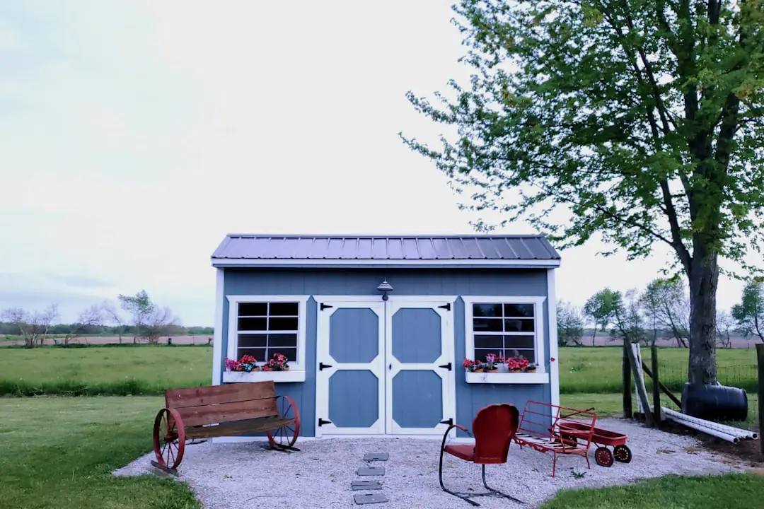 Cabanon de jardin en bois transformé en salon lumineux, ouvert sur un jardin fleuri avec mobilier sobre