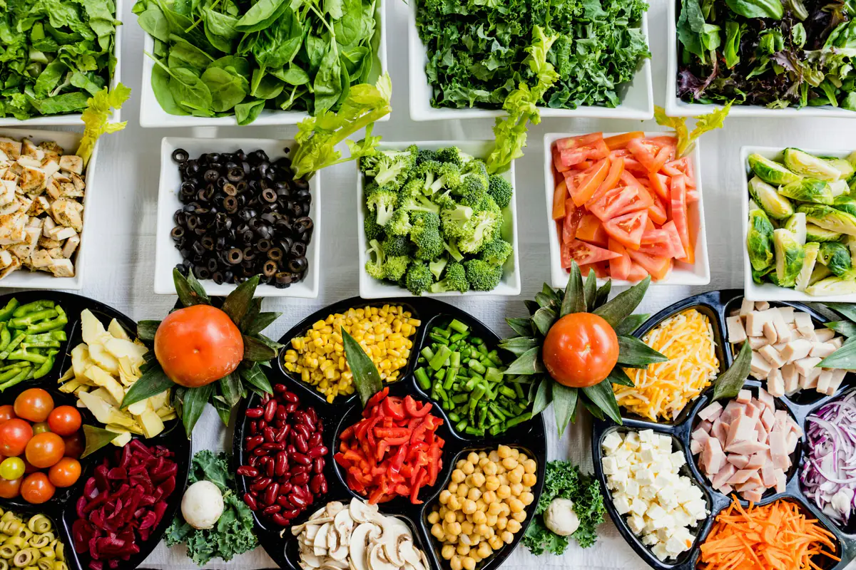 Jardinière âgée et enfants récoltant des tomates cerises dans un potager partagé et paillé