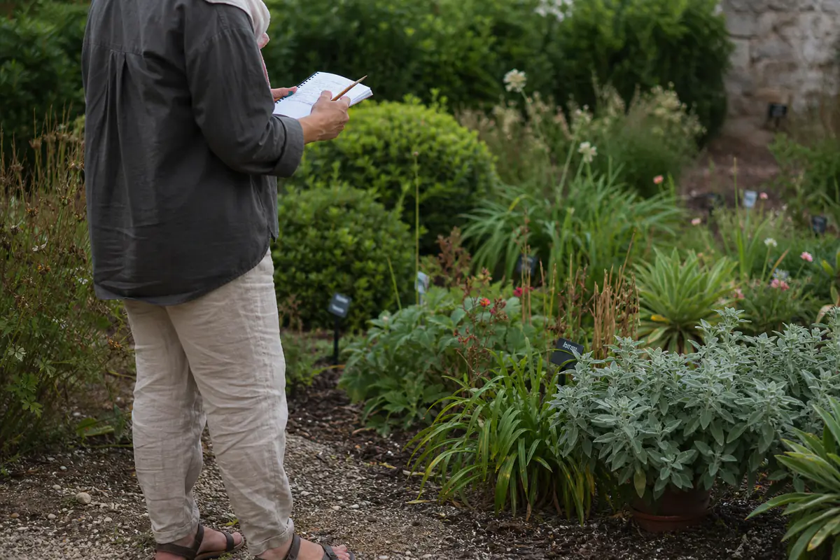 Jardinière prenant des notes devant des vivaces étiquetées lors d’une journée de découverte des plantes