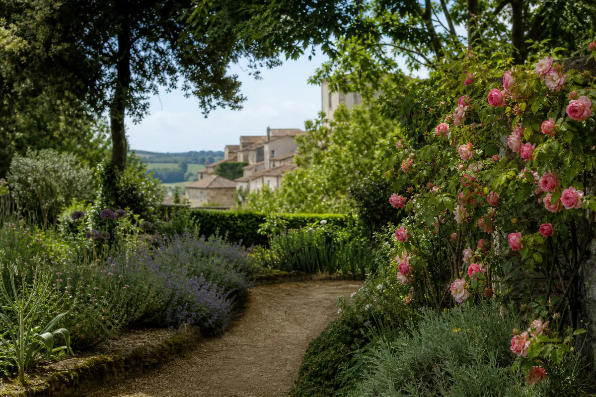Allée des Jardins de Coursiana à La Romieu bordée de roses, lavandes et arbres sous le soleil du Gers