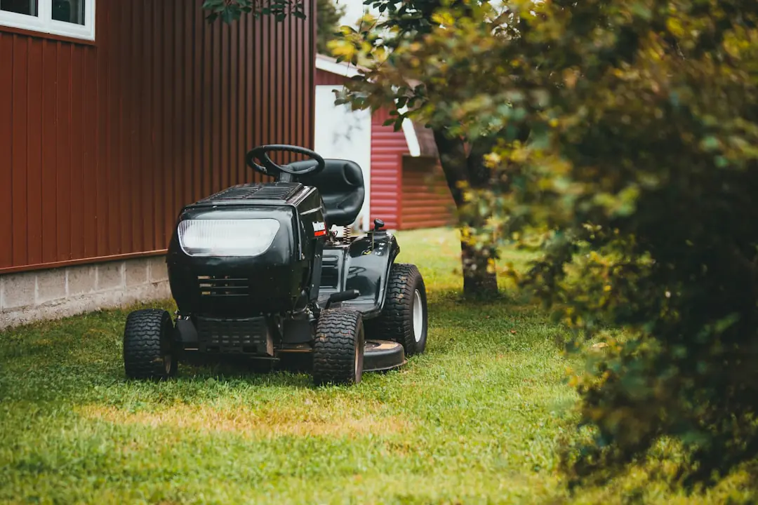 Tondeuse thermique autotractée compacte en action sur une pelouse de jardin français avec bac de ramassage.