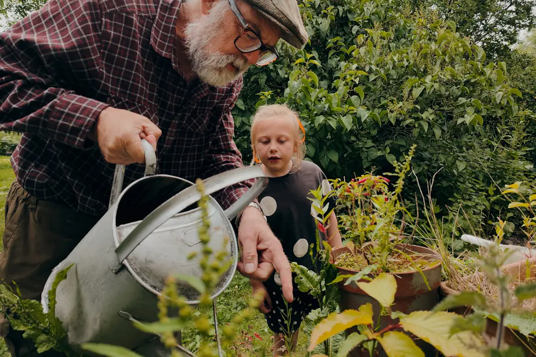 Famille réalisant un semis de radis dans des bacs en bois au soleil, dans un jardin français fleuri
