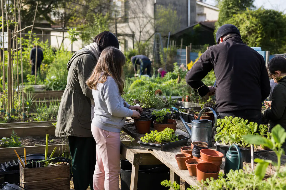 Familles participant à un atelier de semis et de paillage lors de portes ouvertes écologiques dans un jardin collectif