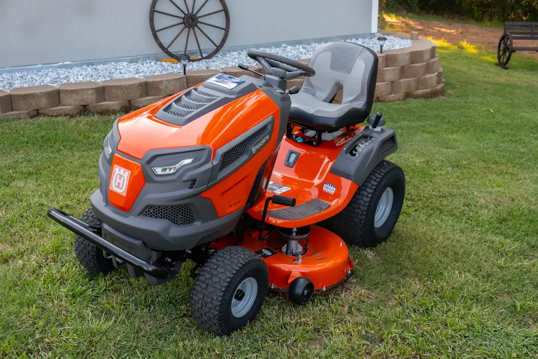 Tondeuse réglée haut sur une pelouse sèche d’un jardin français, entourée de feuilles d’automne ramassées