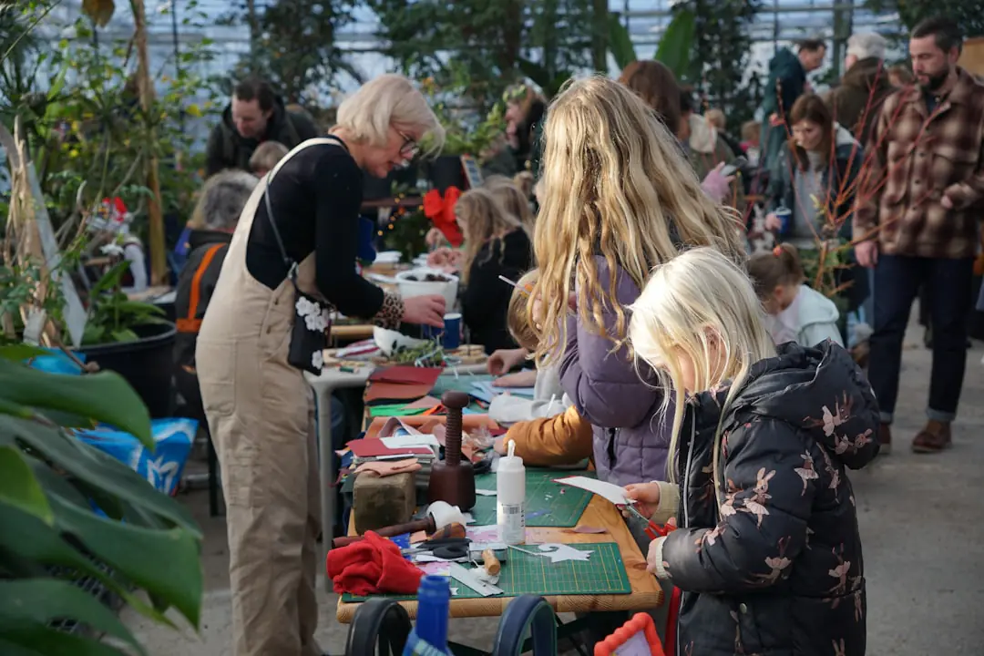 Visiteurs choisissant des vivaces en godets sur des stands de pépiniéristes dans un jardin français