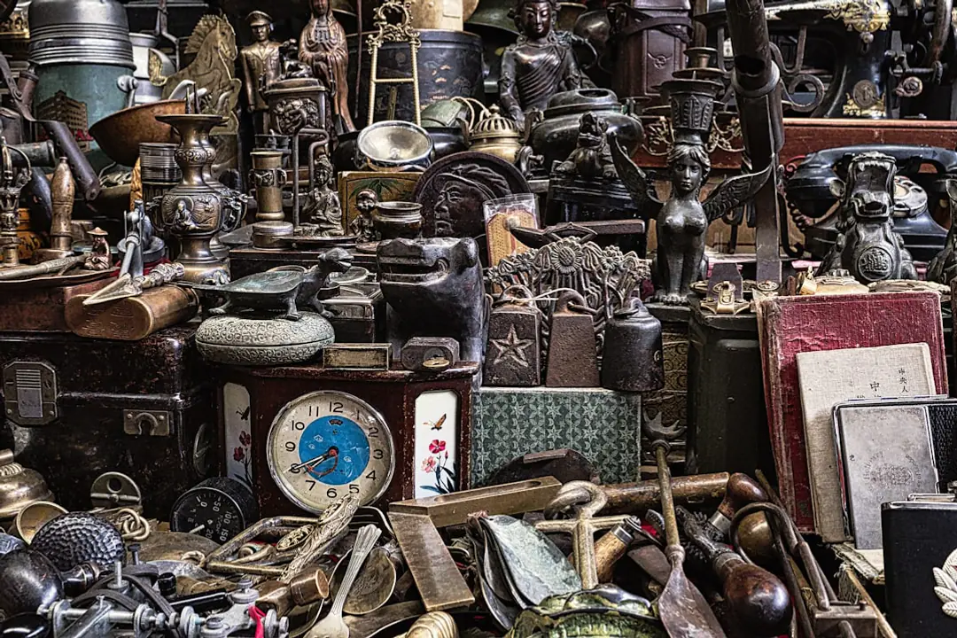Brocante de jardin en plein air avec outils anciens, pots en terre cuite et plantes étiquetées sur des tables