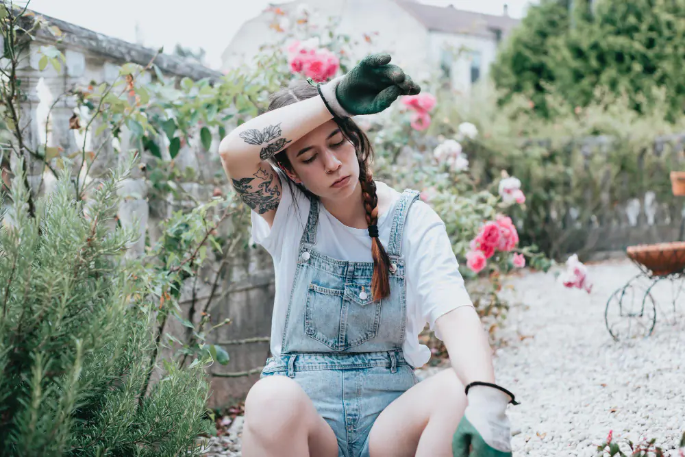 Jardinière débutante plantant de jeunes fleurs colorées dans un massif de jardin au soleil doux