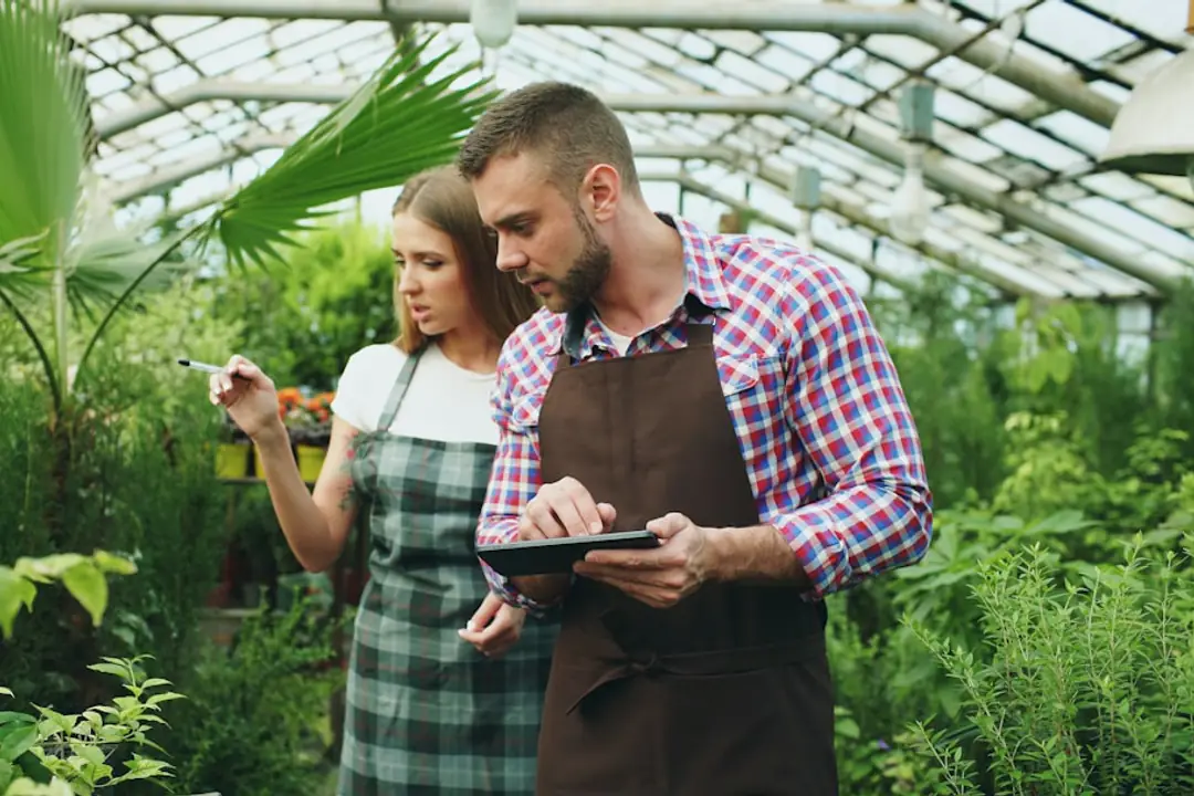 Voisins réunis autour de bacs potagers paillés, préparant des semis dans un jardin partagé lumineux
