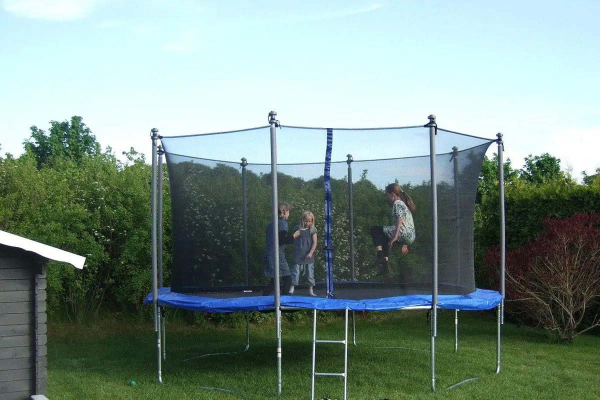 Aire de jeux en bois dans un jardin familial, avec balançoire, copeaux au sol et espace dégagé