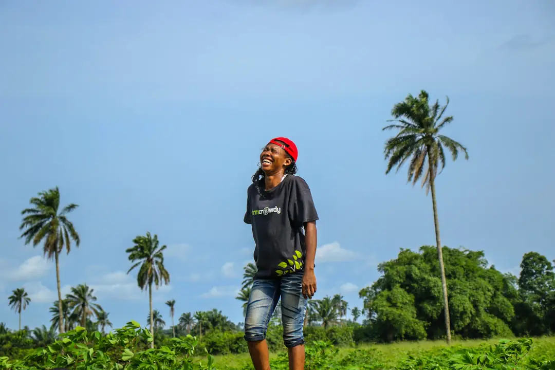 Racine de manioc fraîche épluchée près d’une casserole, avec un plant de manioc sous serre en arrière-plan