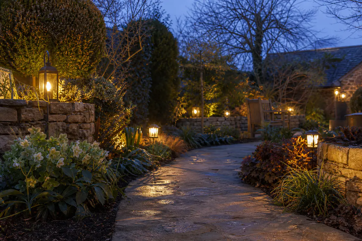 Jardin d’hiver français décoré de lanternes électriques, d’hellébores en pots et de feuillages persistants au crépuscule