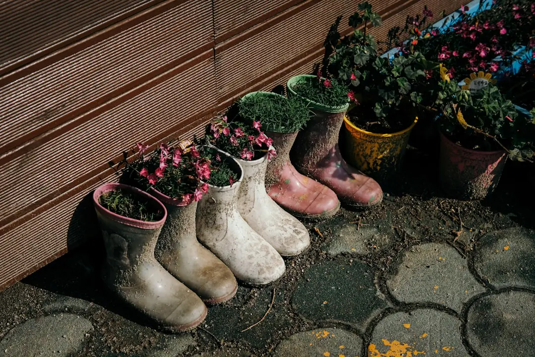 Jardinier observant un jeune plant jauni dans un potager paillé, carnet et transplantoir à la main