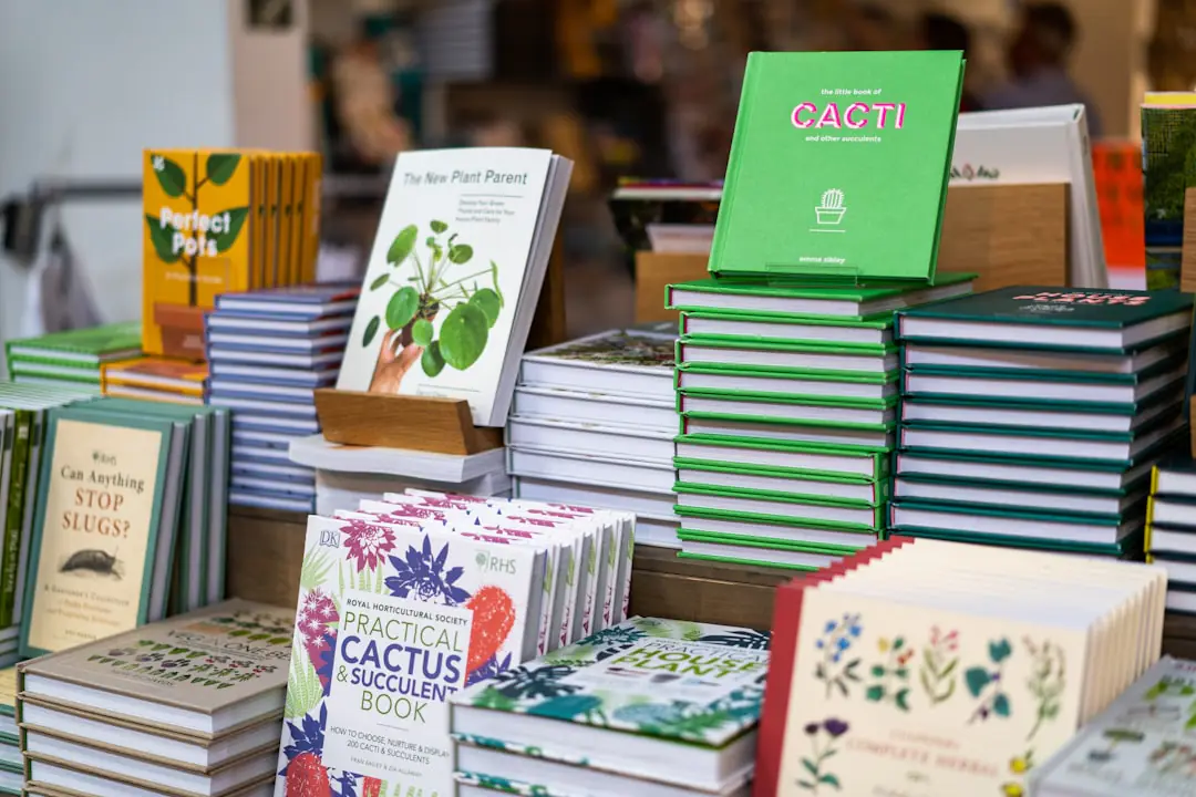 Livres de jardinage ouverts sur une table en bois, entourés de semis, d’un carnet et d’outils dans un jardin français