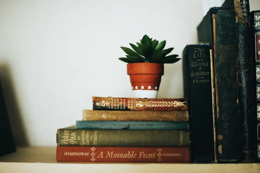 Sélection de livres de jardinage ouverts sur une table en bois devant un potager français au printemps
