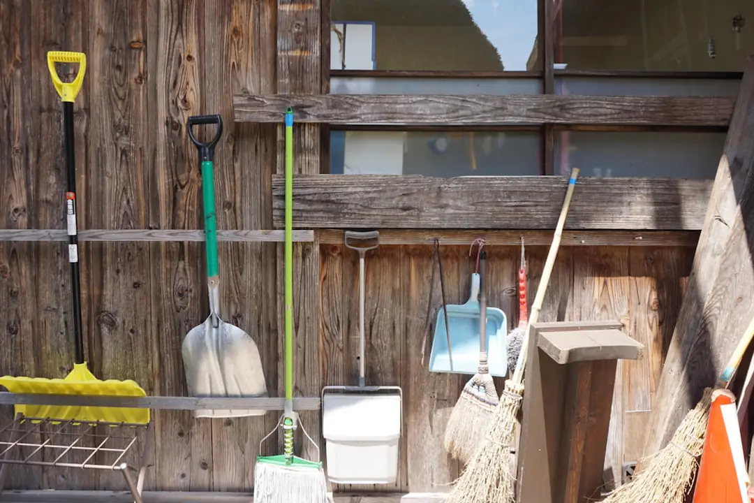 Trois outils de jardin sans fil rangés sur un établi en bois dans un jardin français entretenu