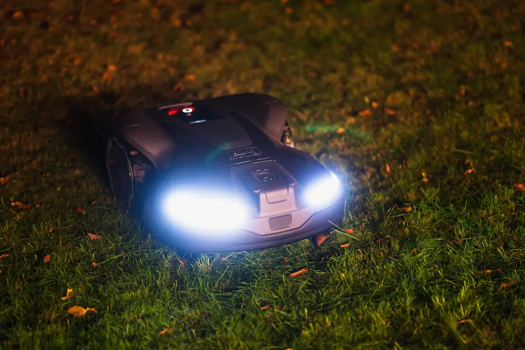 Robot tondeuse autonome coupant une pelouse dense près de bordures fleuries dans un jardin français ensoleillé