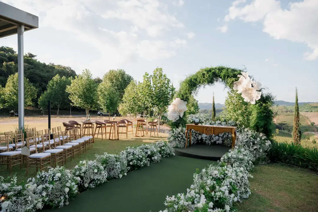 Réception de mariage élégante dans un jardin français, tables fleuries, guirlandes et allée dégagée