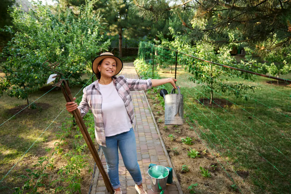 Kit d’outils de jardinage essentiels posé sur une table en bois près d’un potager familial français