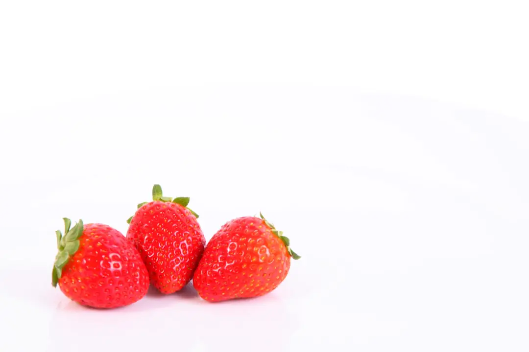 Terrine de semis de fraisiers sur rebord lumineux, graines en surface et jeunes plantules vertes