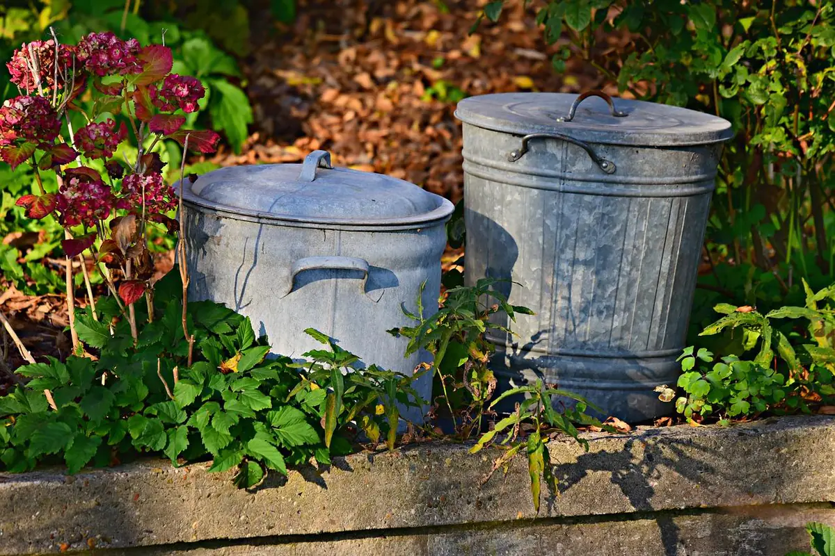 Jardinier français triant feuilles, tontes et rameaux près d’un composteur et d’un paillage au jardin