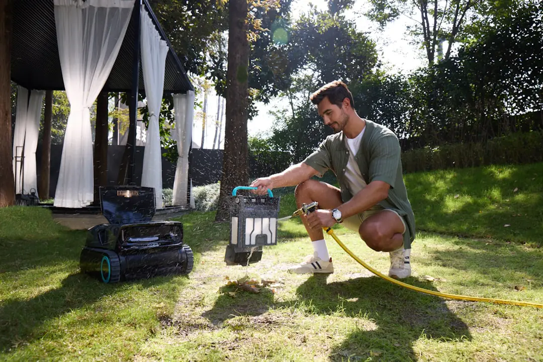 Robot tondeuse compact guidé par câble périphérique sur une pelouse familiale bordée de massifs