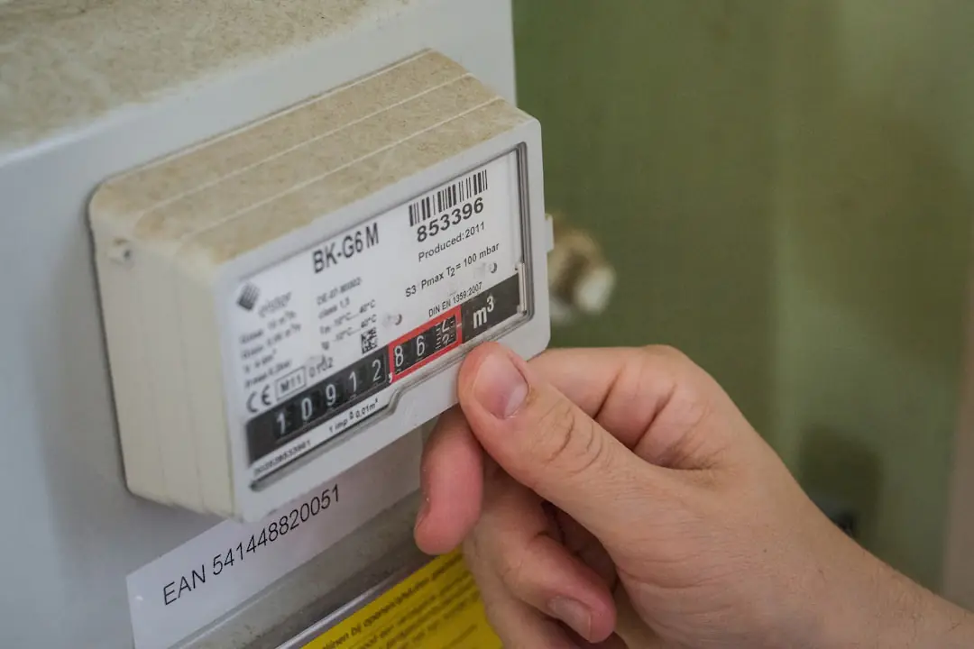 Jardinier stoppant ses travaux près d’un coffret de compteur de gaz dégagé dans un jardin résidentiel.