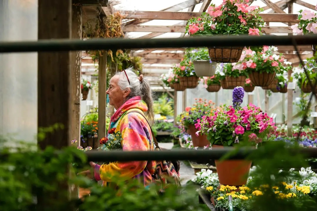 Jardinière française vérifiant ses outils, ses raccords d’arrosage et ses sachets de graines dans un abri rangé.