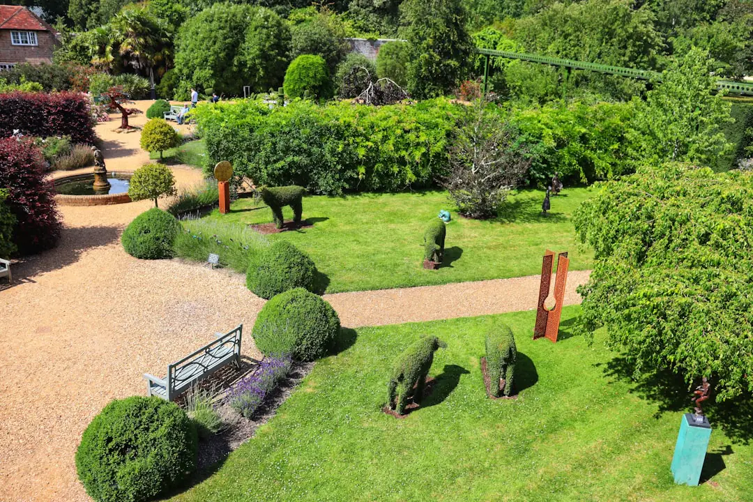 Jardinière arrosant au pied des rosiers et vivaces fleuris dans un jardin français lumineux de juin