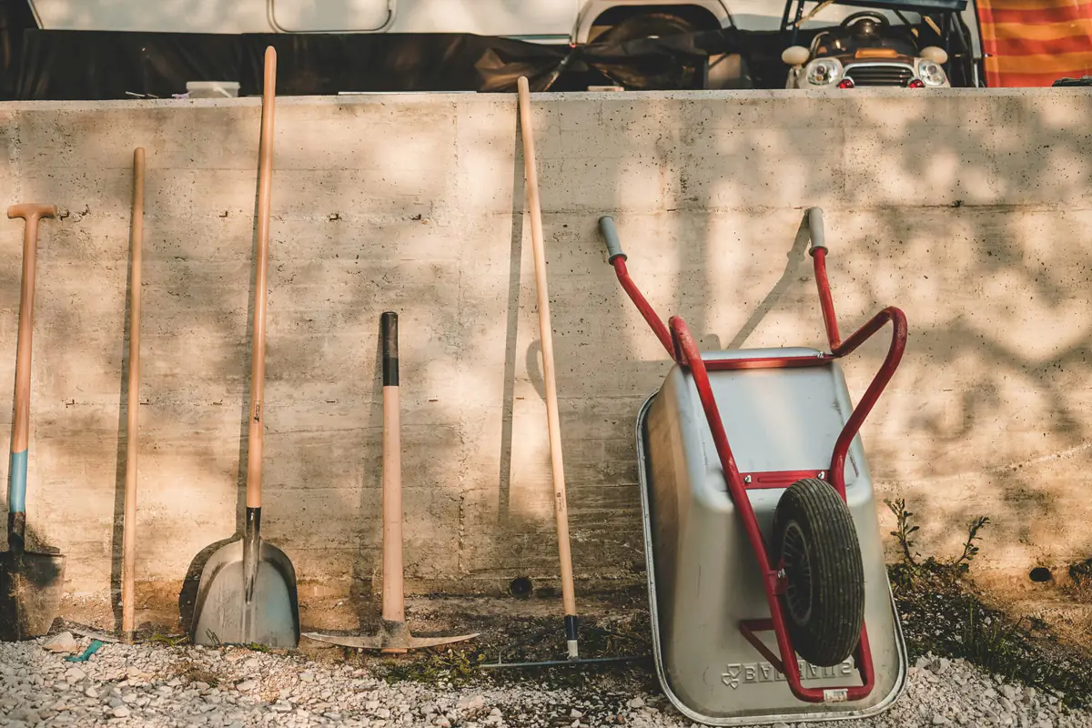 Ensemble d’outils de jardinage durables posés sur un établi près d’un potager français entretenu