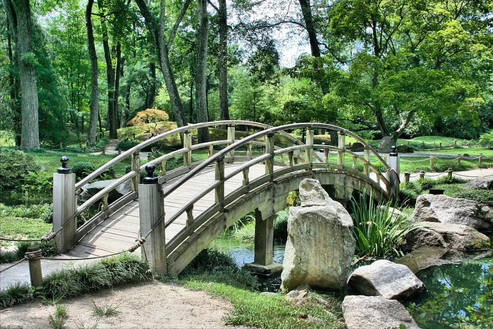 Jardin français harmonieux mêlant terrasse en pierre, massif de vivaces, arbustes et chemin courbe vers un coin repos